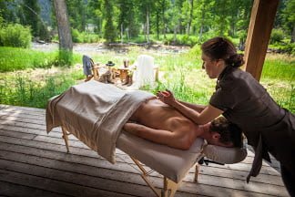 a photo of a woman getting a massage outsidea and 5 seriously cool glamping spots to visit in 2023
