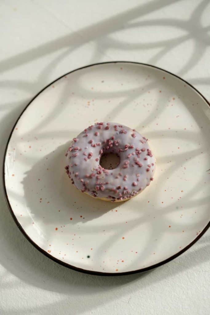 A photo of a donut with lavender glaze on a plate and 11 Healthy Dessert recipes you should try