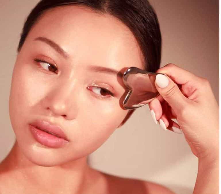 Woman using Sacheu Gua Sha stainless steel tool
